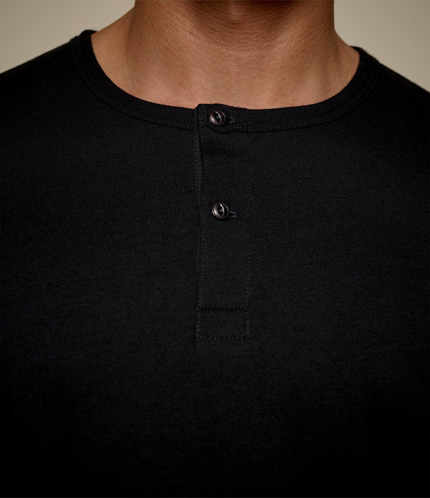 Close-up of button border of black henley with tonal buttons