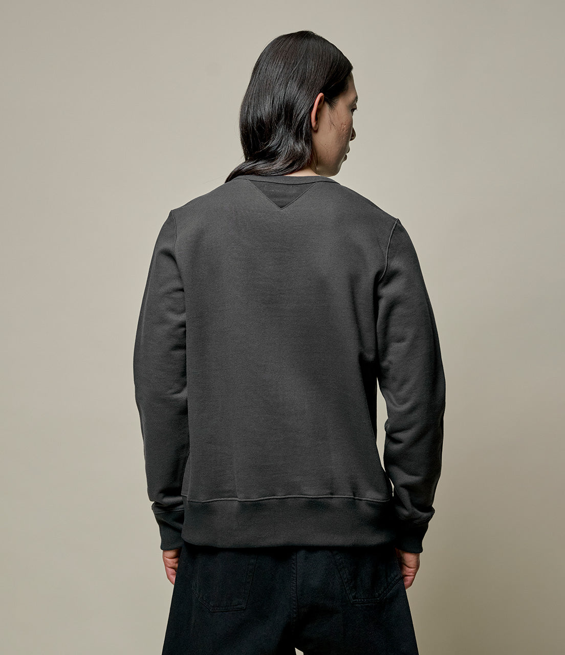 Person wearing a dark gray sweatshirt in a minimal setting