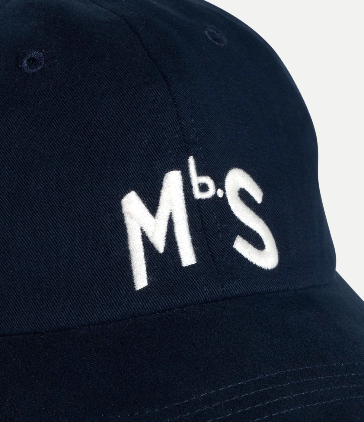 Navy blue cap with 'Mbs' logo on a light gray background
