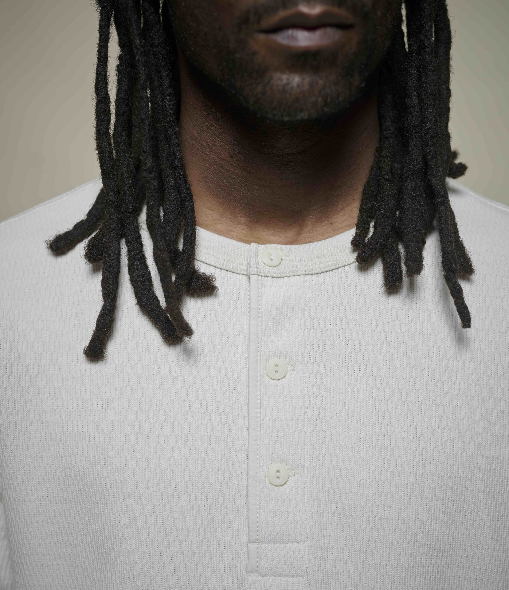 Person wearing a light-colored henley shirt against a neutral background