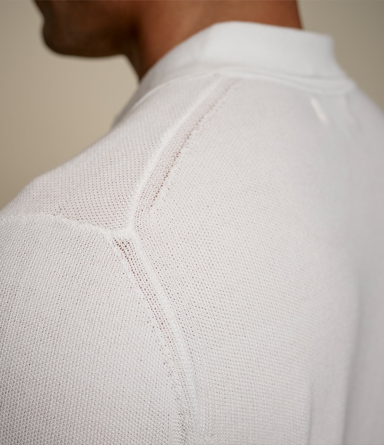 Close-up of a white knitted polo shirt with a plain background