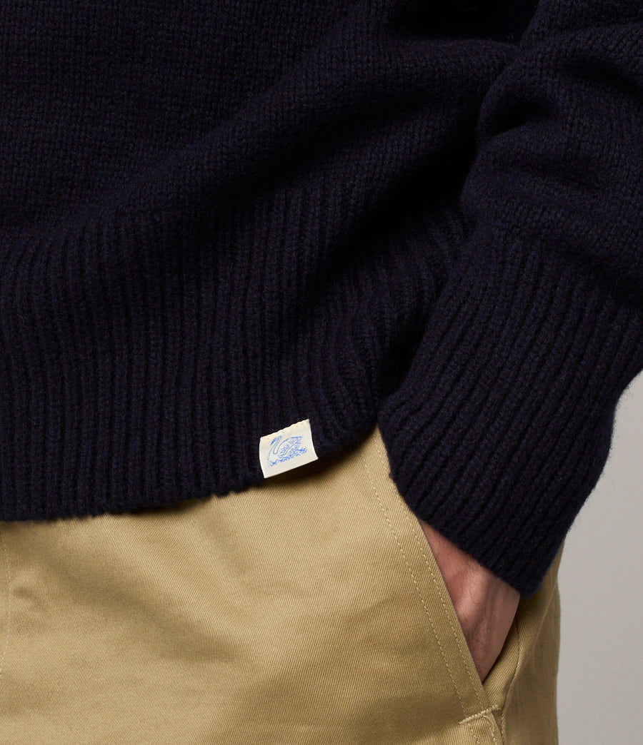 Close-up of a navy sweater with a brand label on a neutral background