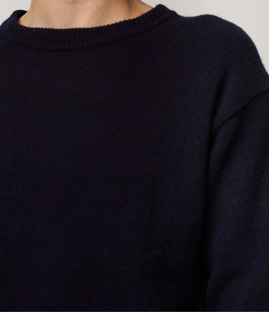 Close-up of a person wearing a dark blue sweater against a neutral background