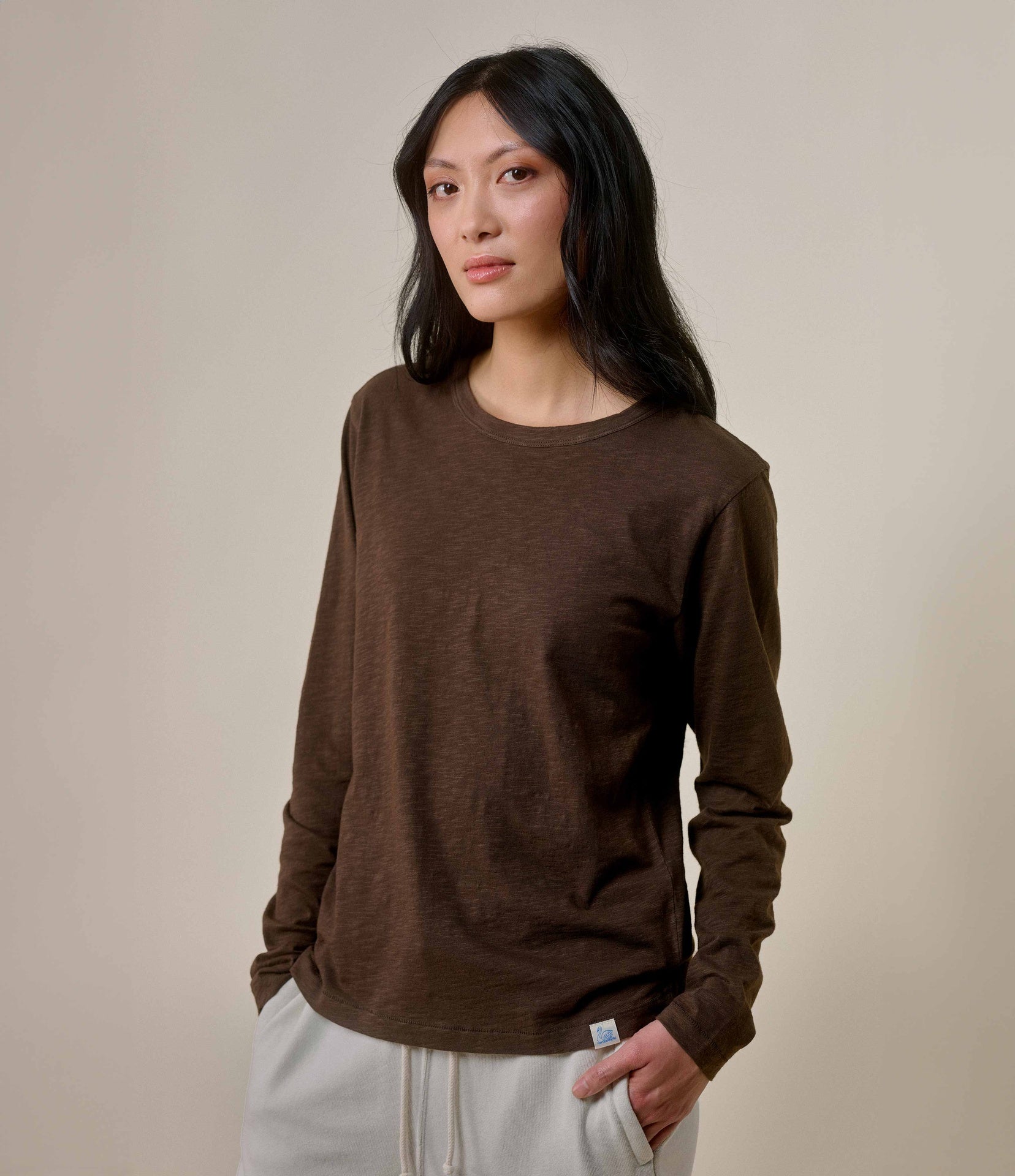 A woman wearing a brown long-sleeve T-shirt with a round neckline.