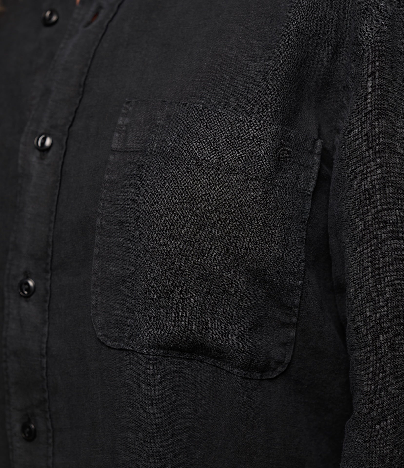 Close-up of a black button-up linen shirt with a pocket