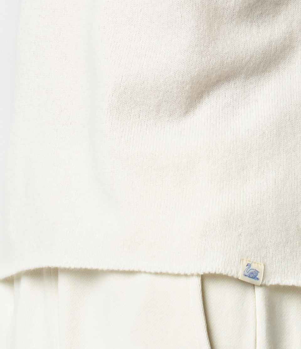 Close-up of sweater made of merino wool, silk and cashmere with label with swan logo on the hem.