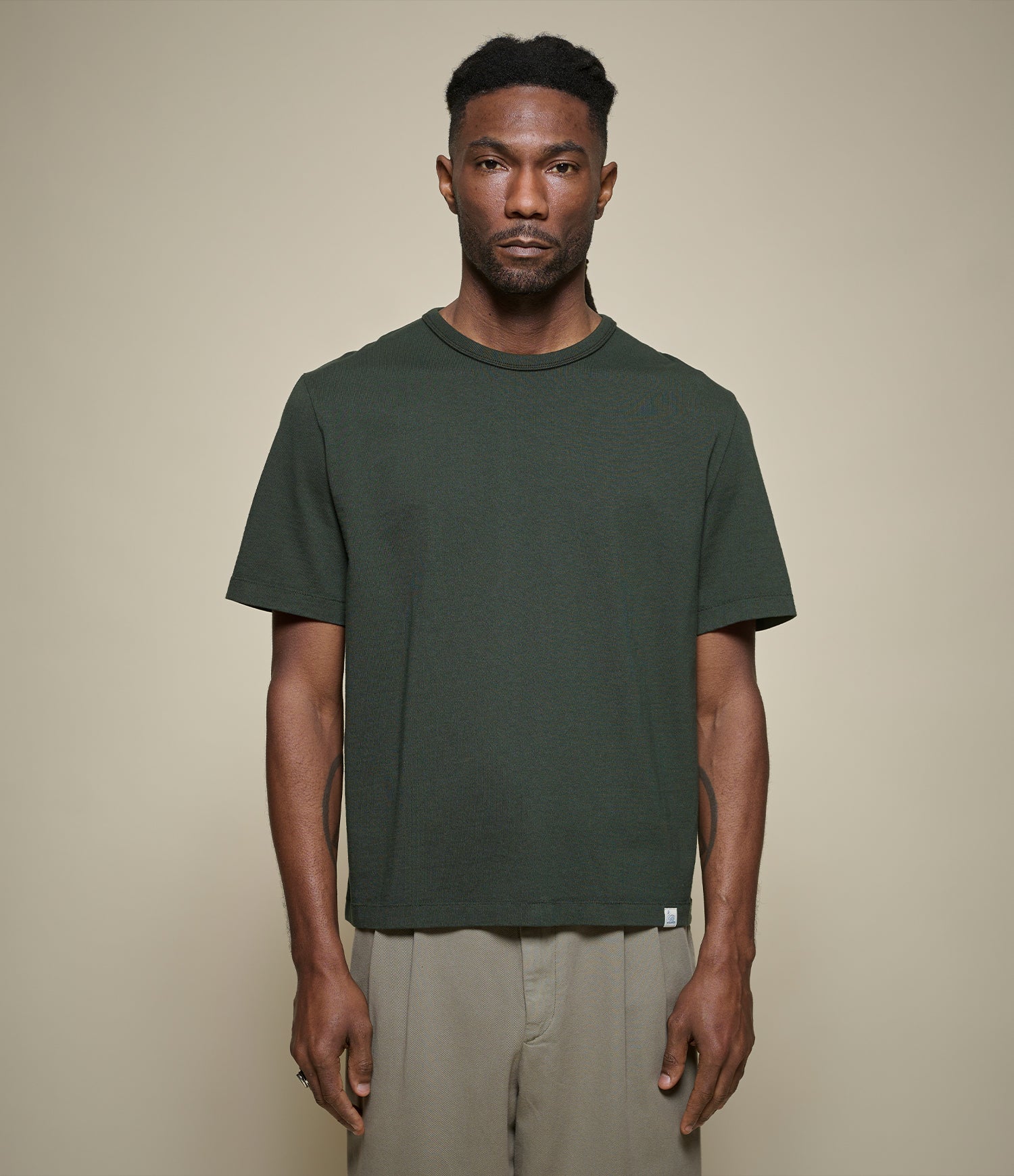 Man wearing a cropped green t-shirt against a beige background