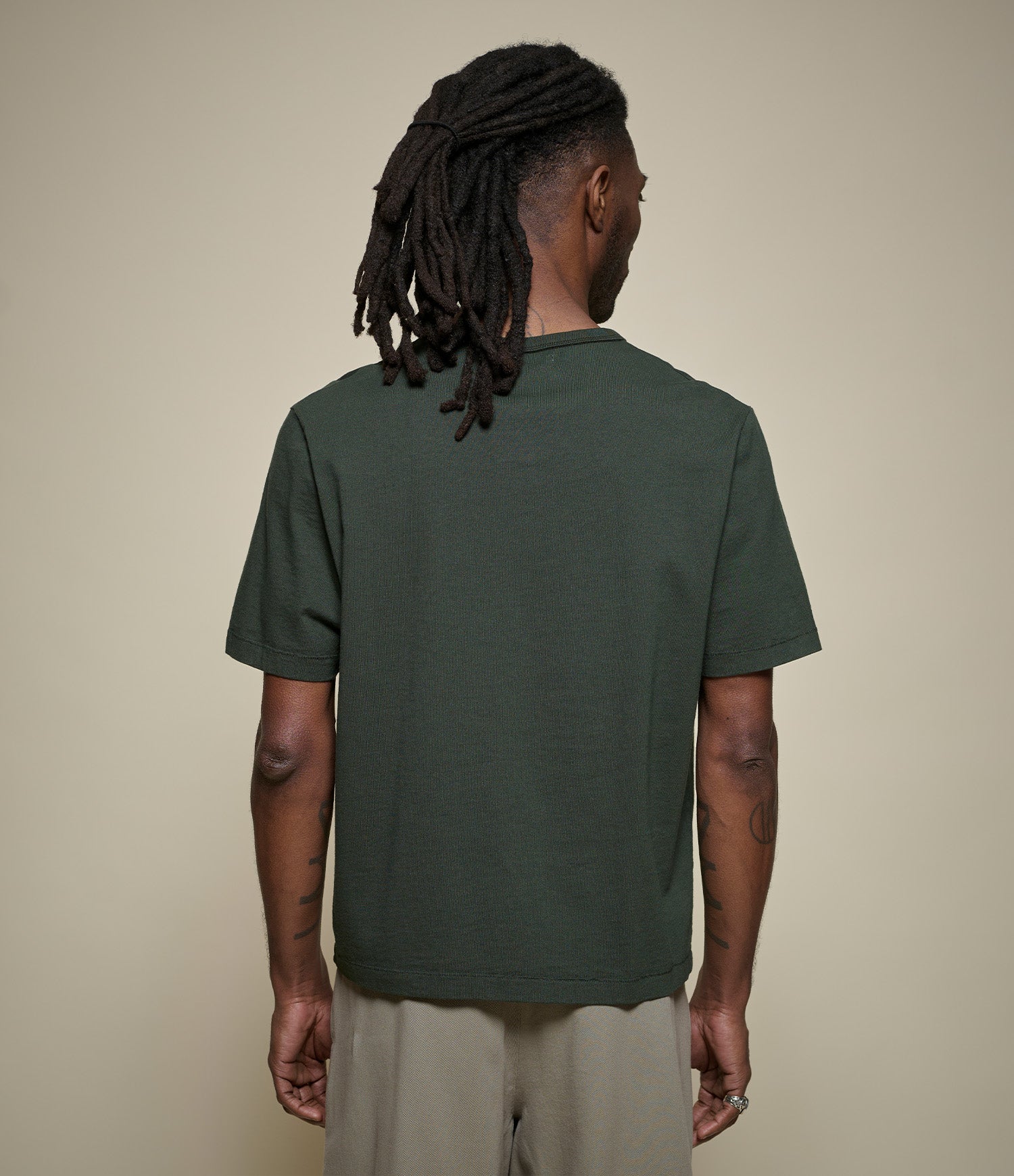 Man wearing a cropped green t-shirt against a beige background