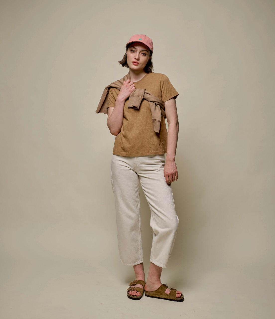 Woman wearing brown hemp-cotton -shirt, beige pants, pink cap and sweatshirt around her shoulders.