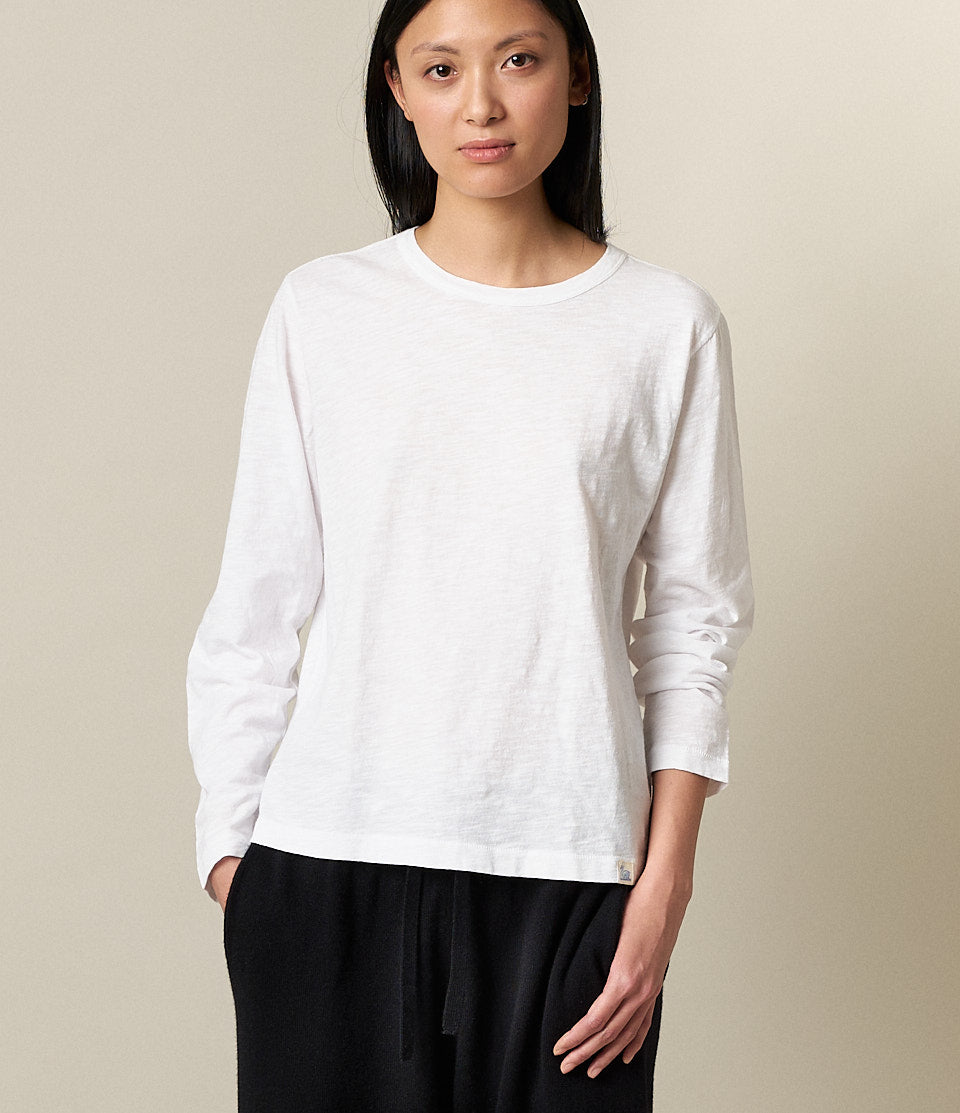 A woman wearing a white long-sleeved T-shirt and black pants.