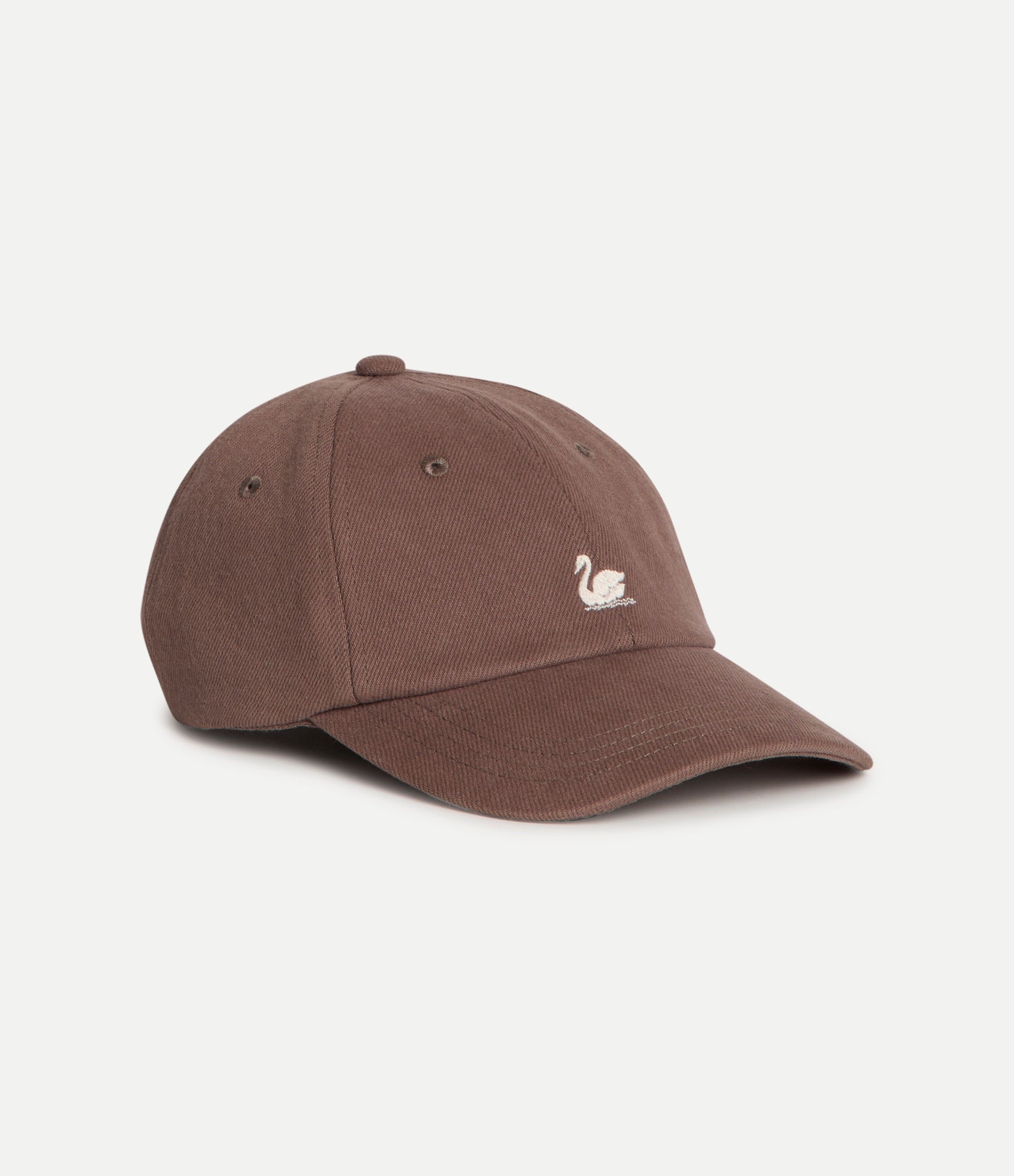 A brown cotton baseball cap with a small white embroidered swan logo on the front, photographed on a clean off-white background.